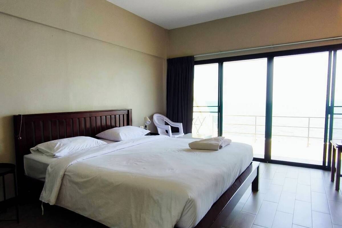Habitación de hotel con una cama grande, una silla, una mesa y un balcón con vistas.
