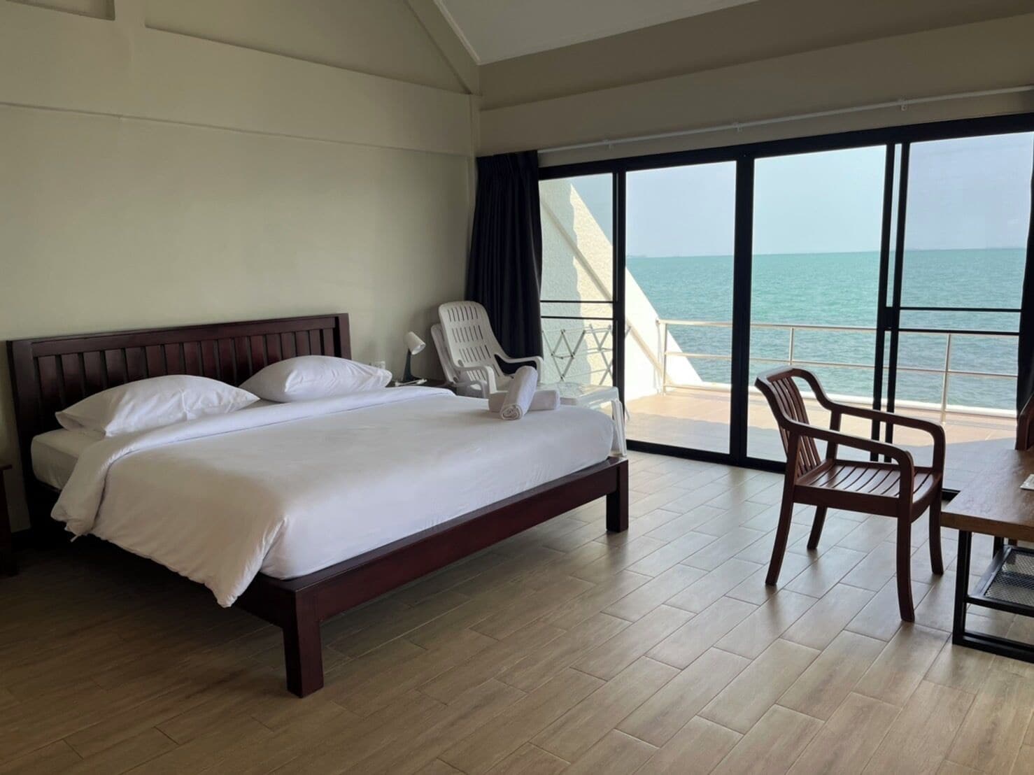 Quarto de hotel com uma cama grande, uma cadeira e vista para o mar.