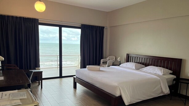 Una habitación de hotel con una cama grande, un escritorio y vista al océano.