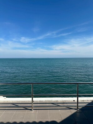 Une vue sur l’océan depuis une terrasse carrelée, protégée par une rambarde en métal.