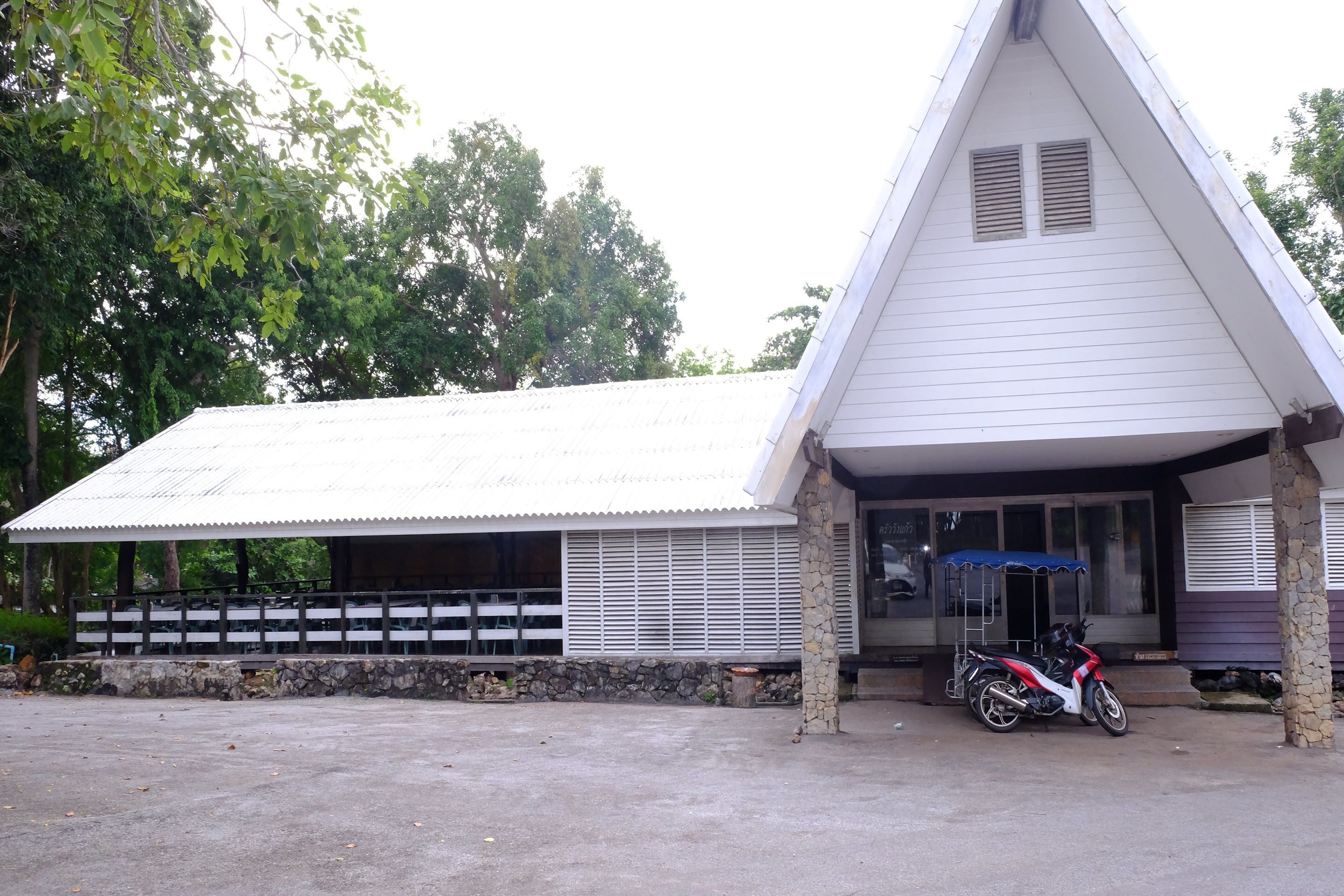 A building with a sloped roof, stone pillars, and a motorcycle parked in front.