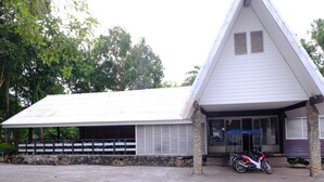 A building with a sloped roof, stone pillars, and a motorcycle parked in front. - Wangkaew Resort (Klaeng)