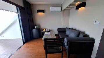 Un espacio habitable compacto con sofá, mesa de comedor y una silla. Hay una puerta corredera que da a un área exterior.