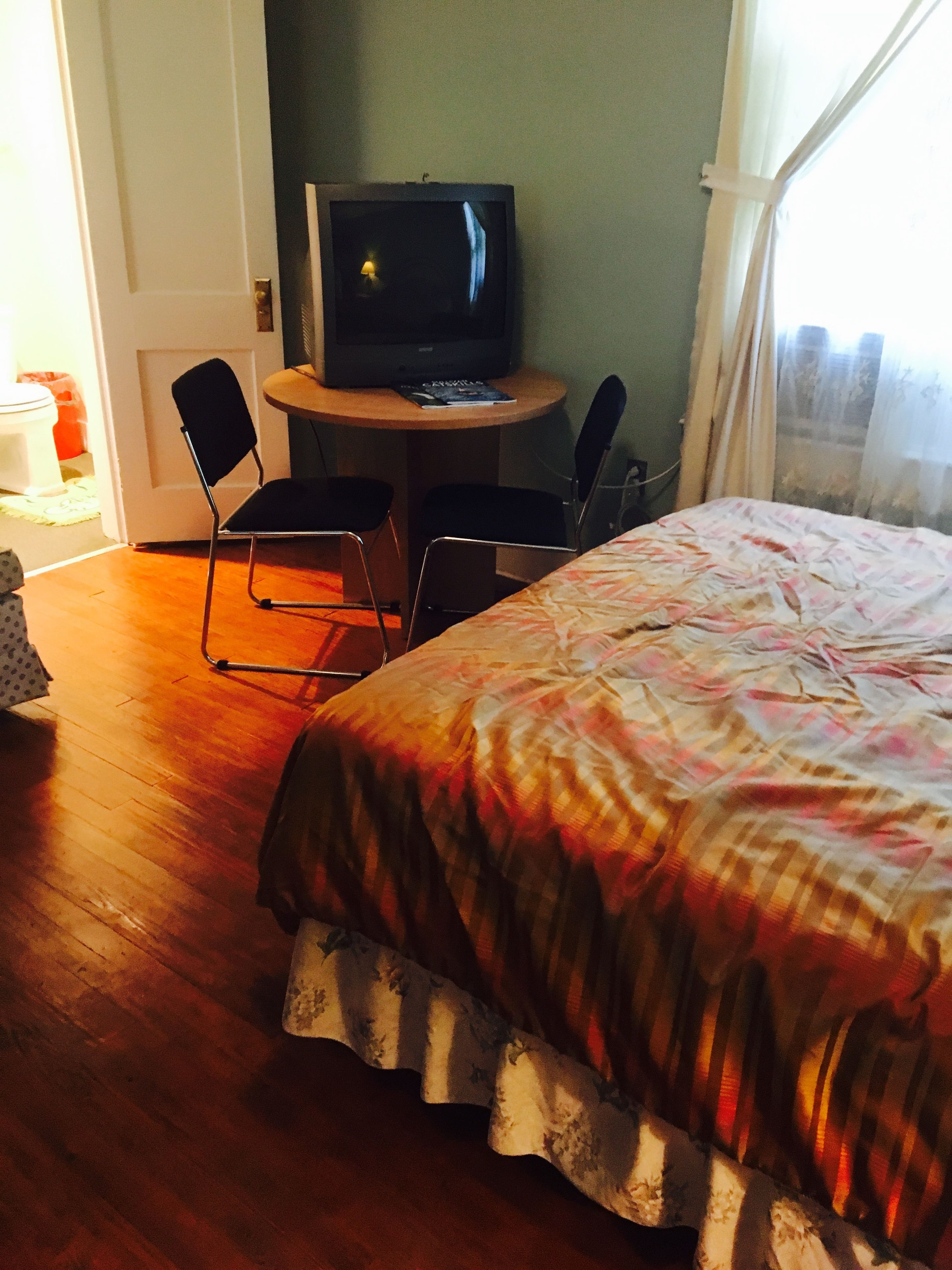 A hotel room with a bed, a television on a small table, and a chair.