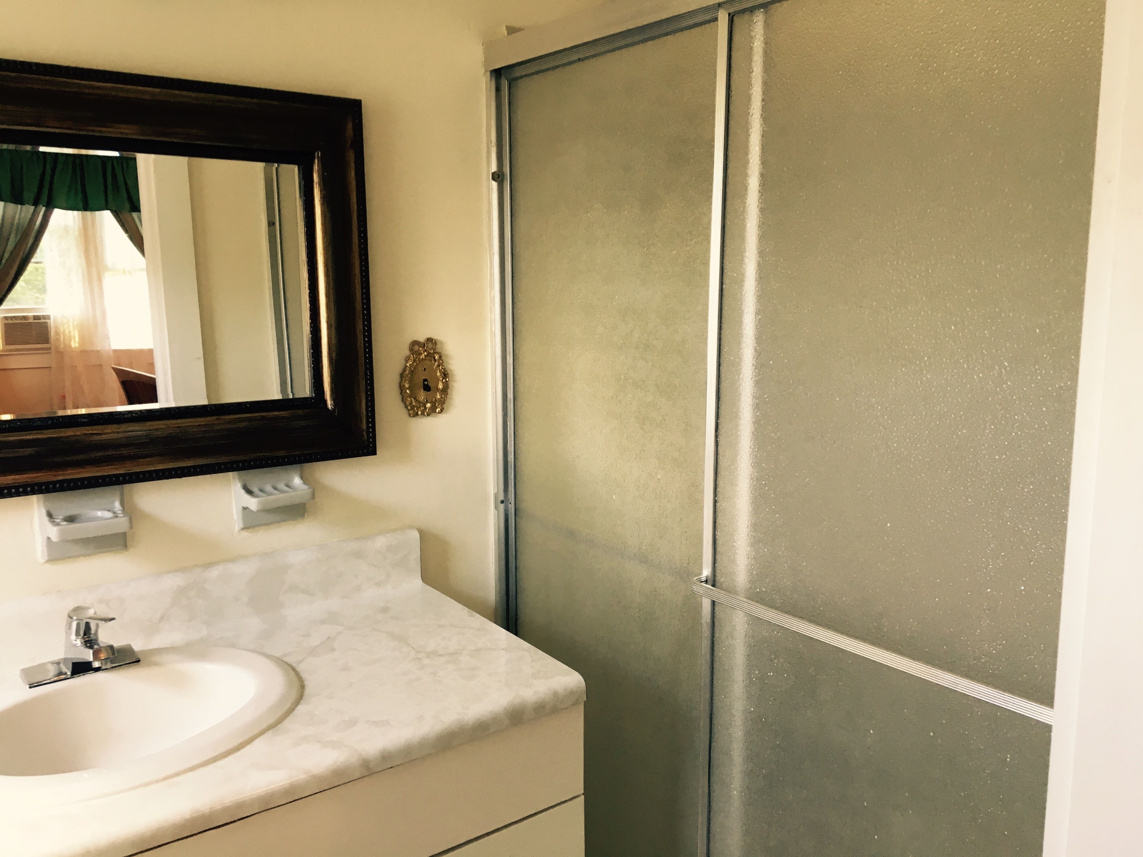 A bathroom with a white sink, a mirror, and a frosted glass shower door.