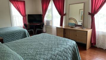 Quarto de hotel com duas camas, televisão, escrivaninha e espelho.