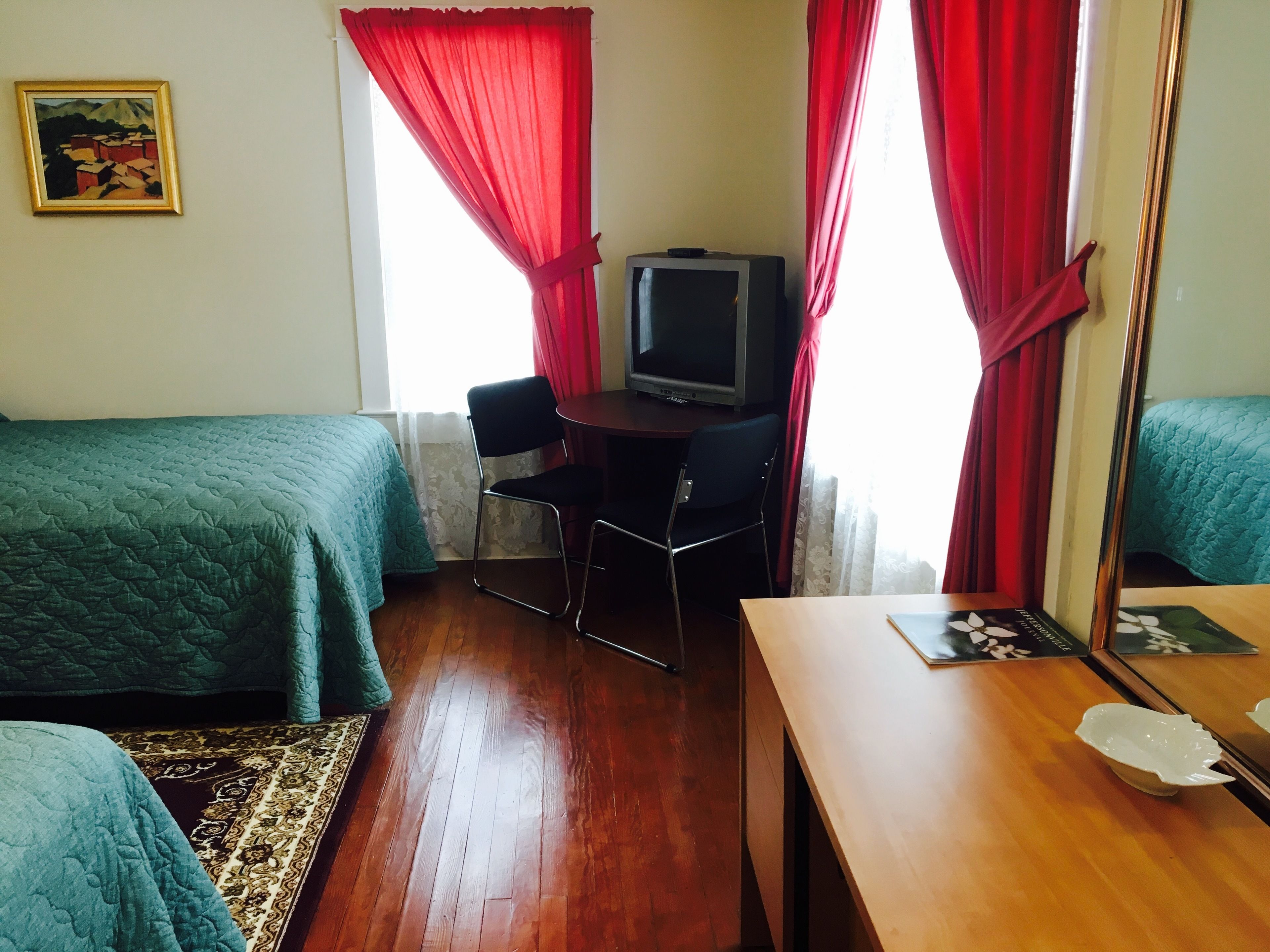 Une chambre avec deux lits, un bureau, une chaise, une télévision et un miroir.