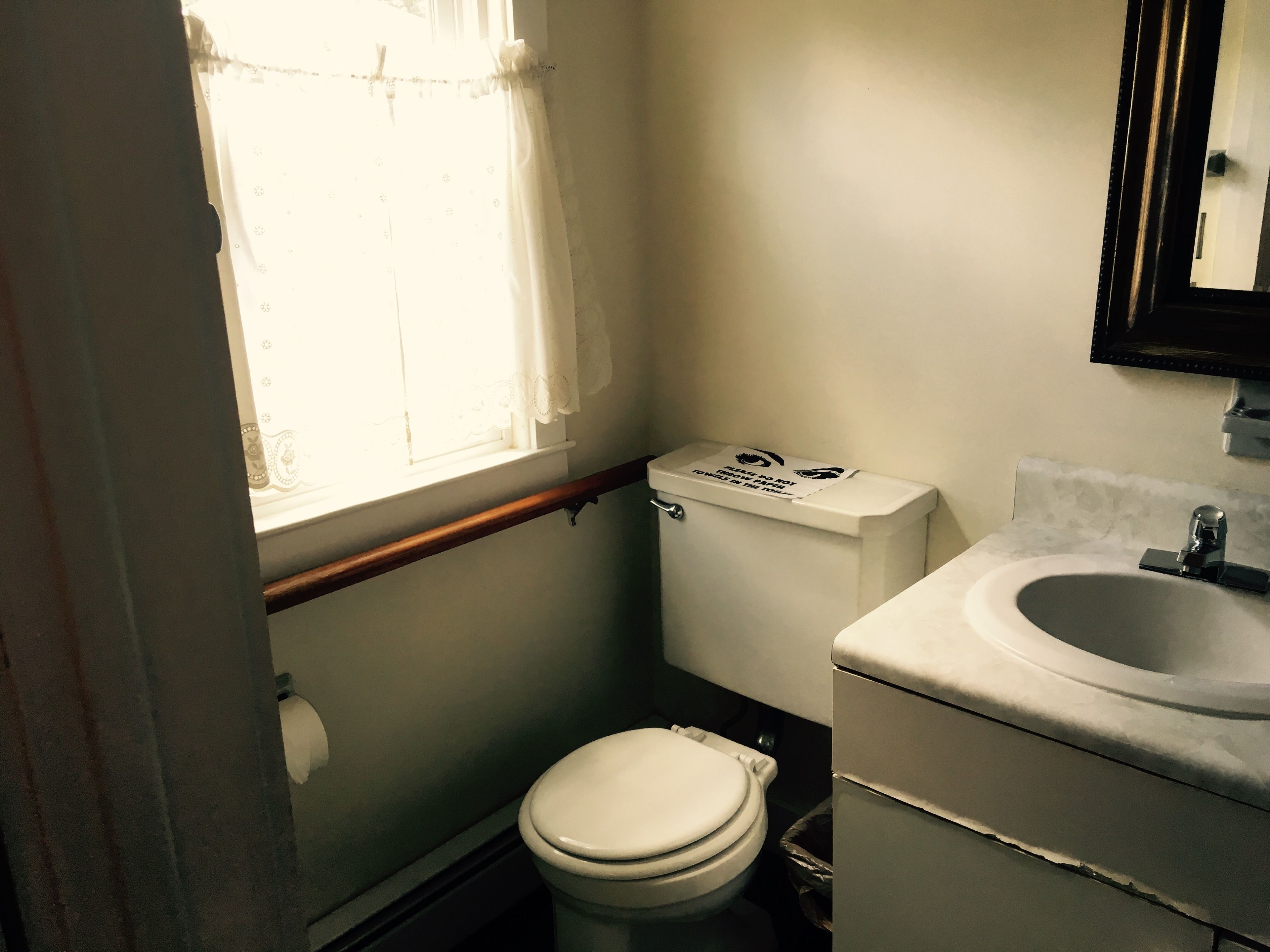 A small bathroom with a toilet, sink, and window.