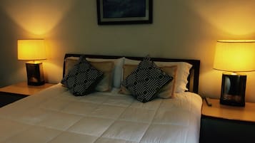 A neatly made bed with a white duvet, two black and white patterned pillows, and two bedside lamps on either side.