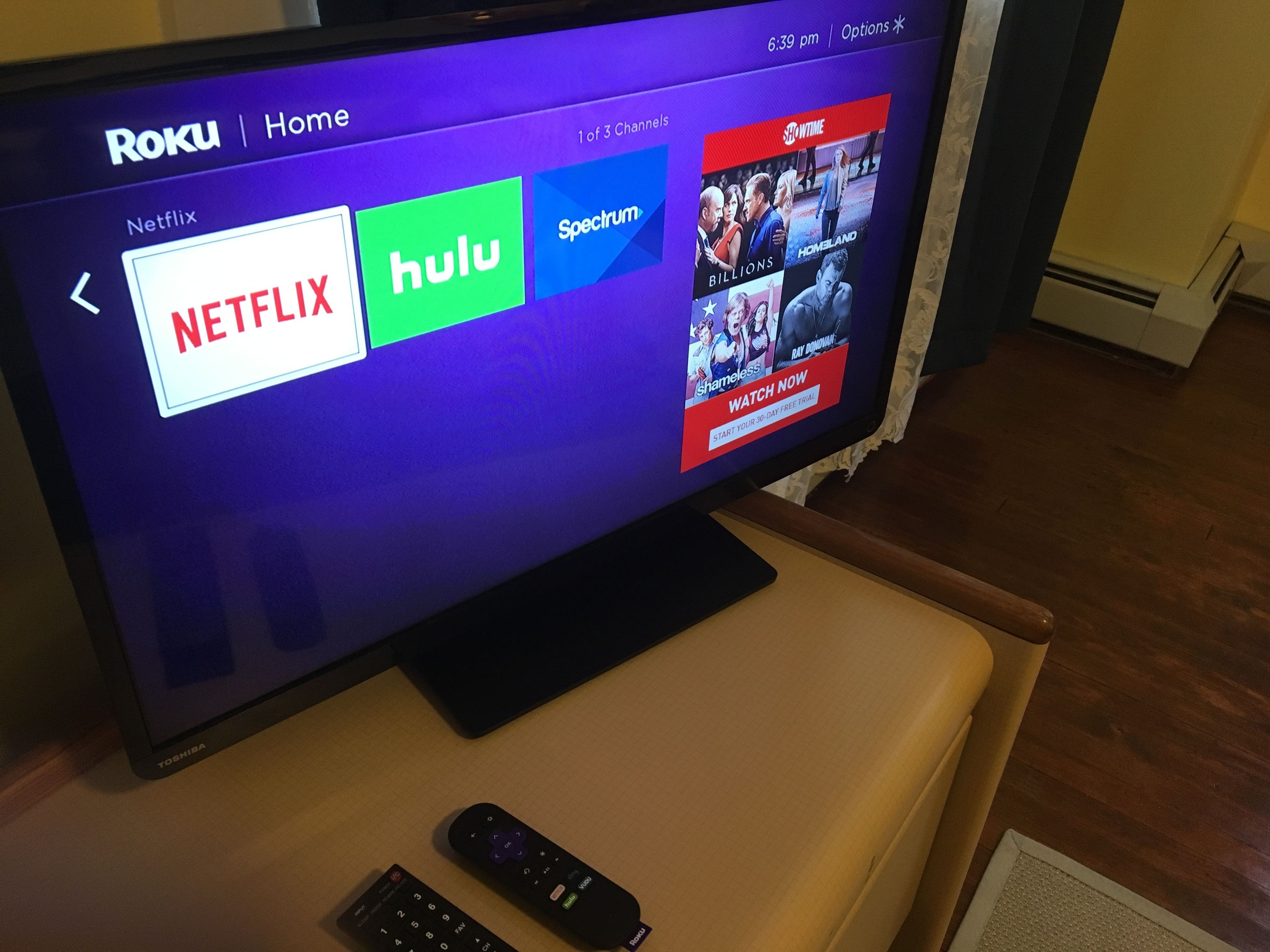 A television displaying Roku interface with Netflix, Hulu, and Spectrum channels.