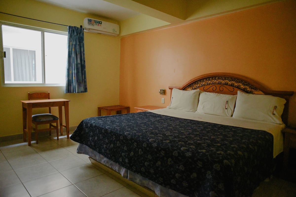A bedroom with a bed, a desk, and a chair.