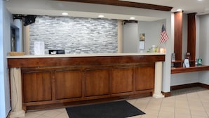 Zona de recepción con pared de piedra, mostrador de madera y una bandera estadounidense.