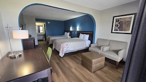 Une chambre d’hôtel avec deux lits, un canapé, un bureau et une lampe.