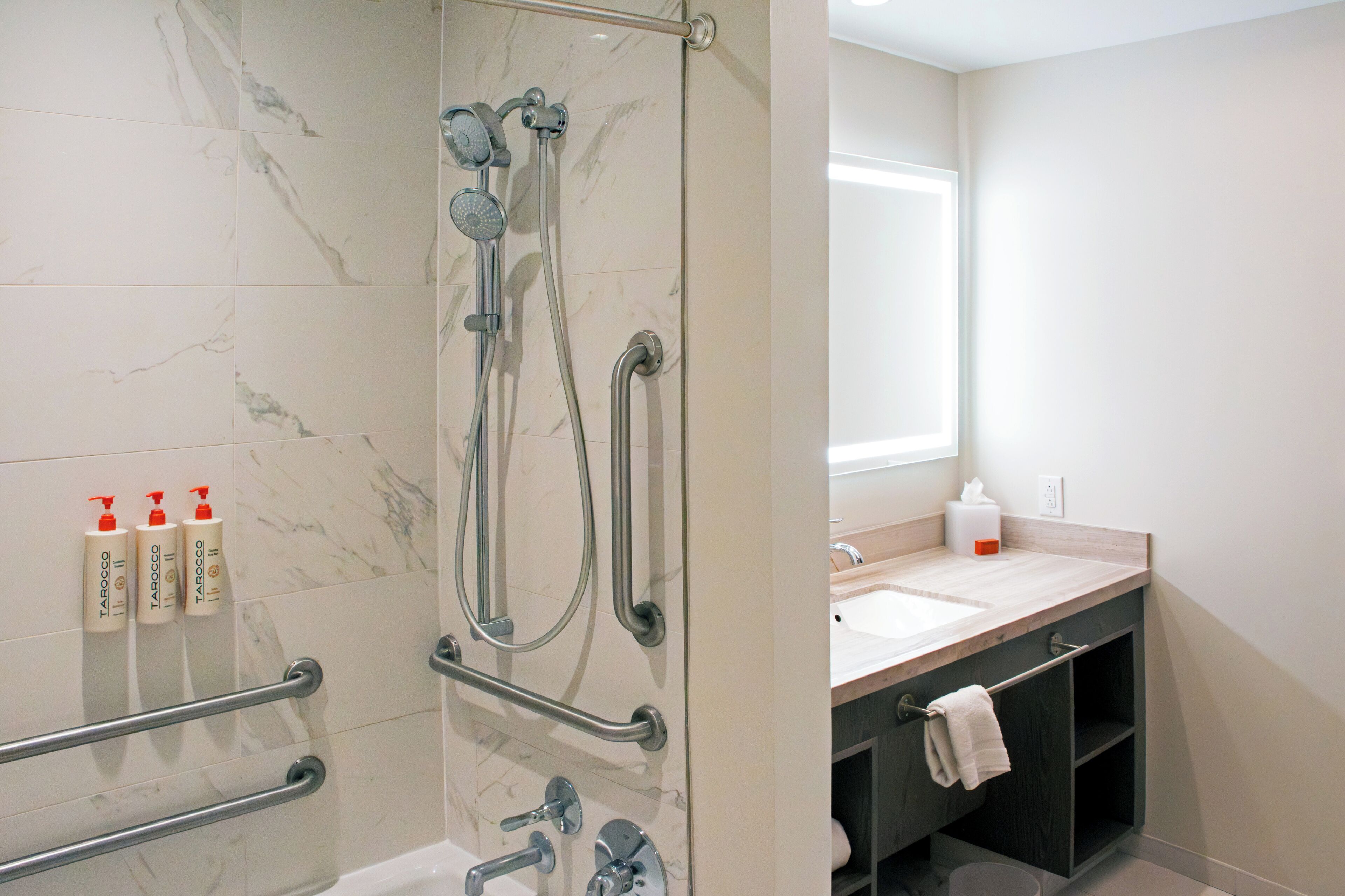 A modern bathroom with a glass-enclosed shower, a vanity with a sink, and toiletries on the wall.