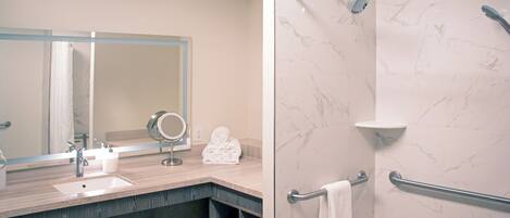 A modern bathroom with a sink, mirror, towel rack, and shower area.