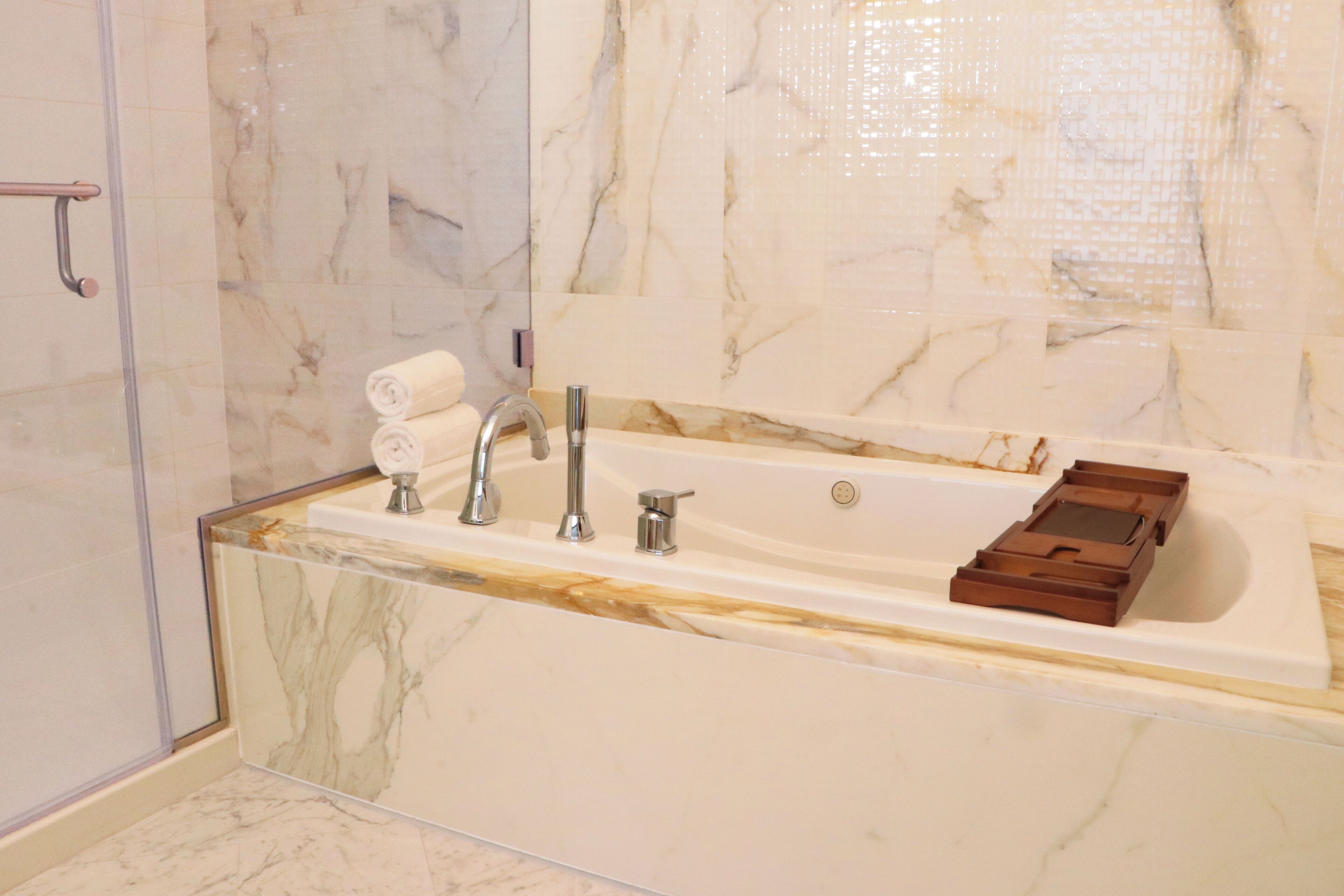 A bathroom with a marble sink, a bathtub, and a shower area.