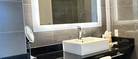 Une salle de bain moderne avec un meuble-lavabo noir, un lavabo blanc et un grand miroir.