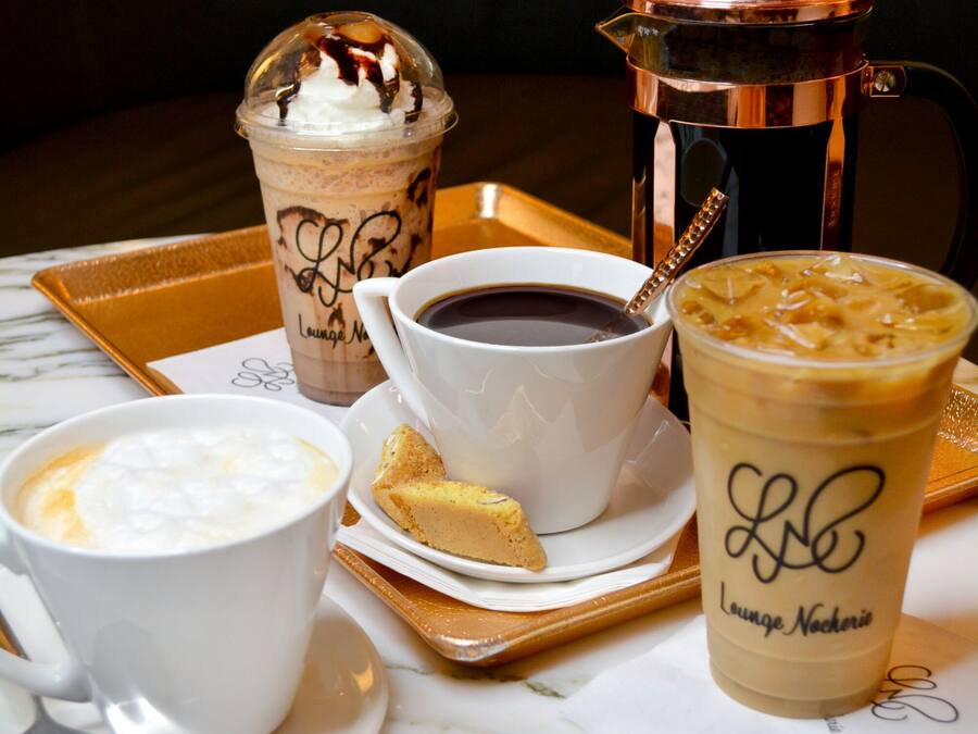 A tray with various beverages and a coffee maker on a marble table.