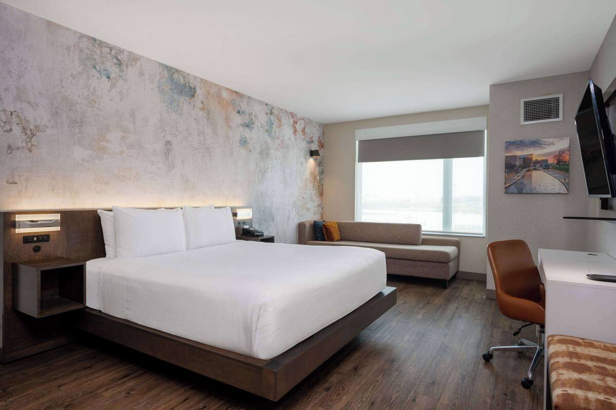 Une chambre d’hôtel moderne avec un grand lit, un canapé, un bureau et une télévision.