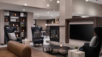 A modern lounge area with leather sofas, a fireplace, and a flat-screen TV.