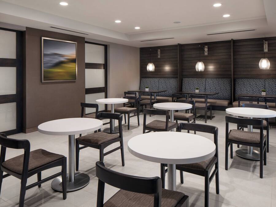 Um restaurante moderno com mesas e cadeiras redondas, um quadro grande na parede e iluminação pendente.