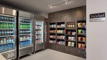 A grocery store interior with refrigerated beverage dispensers, shelves stocked with snacks, and a sign reading "The Market".