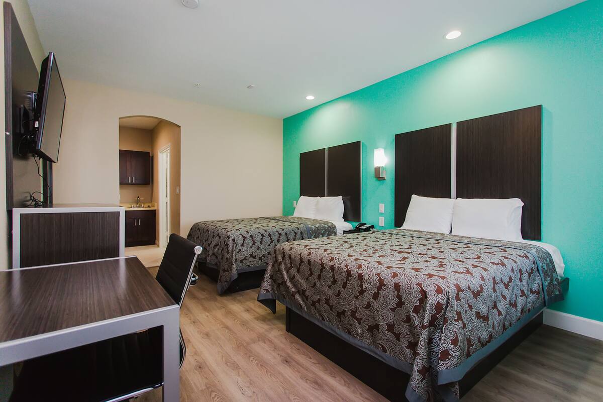 Une chambre d’hôtel avec deux lits, un bureau et une télévision.
