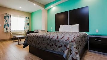 A hotel room with a large bed, a bedside table, a desk, and a chair.