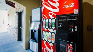 A Coca-Cola vending machine in a hallway with a sign for guest laundry. - Palace Inn and Suites - Willowbrook Mall (Houston)