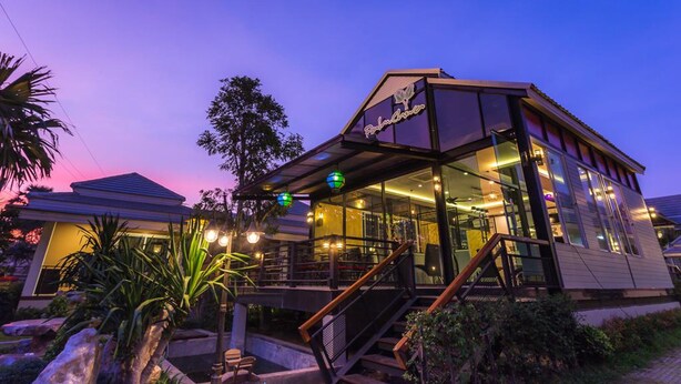 A modern building with a glass facade, a visible staircase, and outdoor seating area. - Palmchwa Resort (Sikhio)