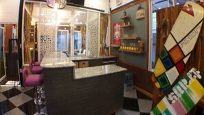 A bar area with a counter, purple bar stools, and a colorful board game on the wall. - Palmchwa Resort (Sikhio)