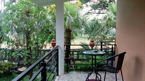 A covered outdoor area with a table and chairs, surrounded by lush greenery and potted plants. - Palmchwa Resort (Sikhio)
