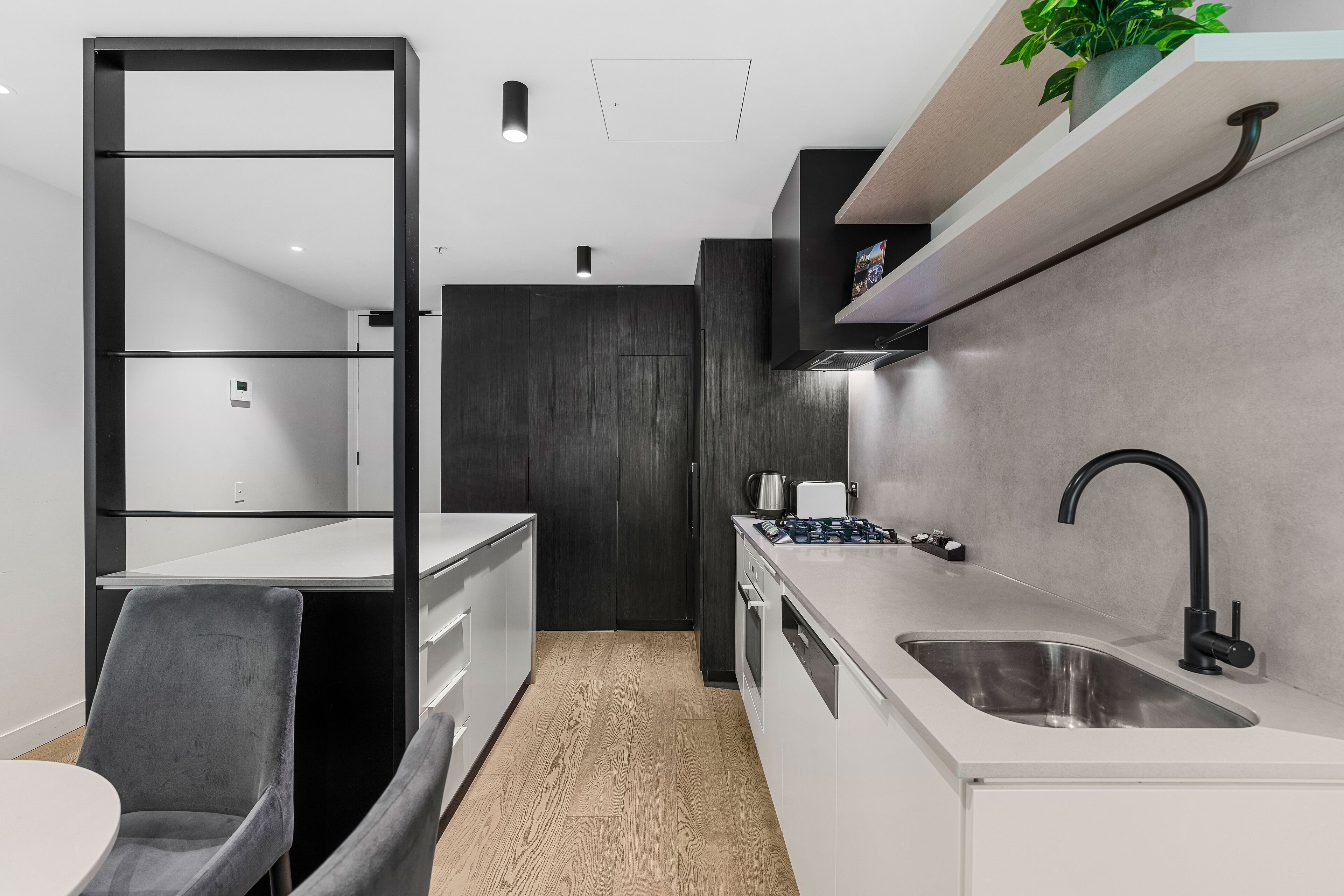 A modern kitchen with a white countertop, black faucet, and a grey chair.