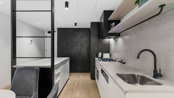 A modern kitchen with a white countertop, black faucet, and a grey chair.