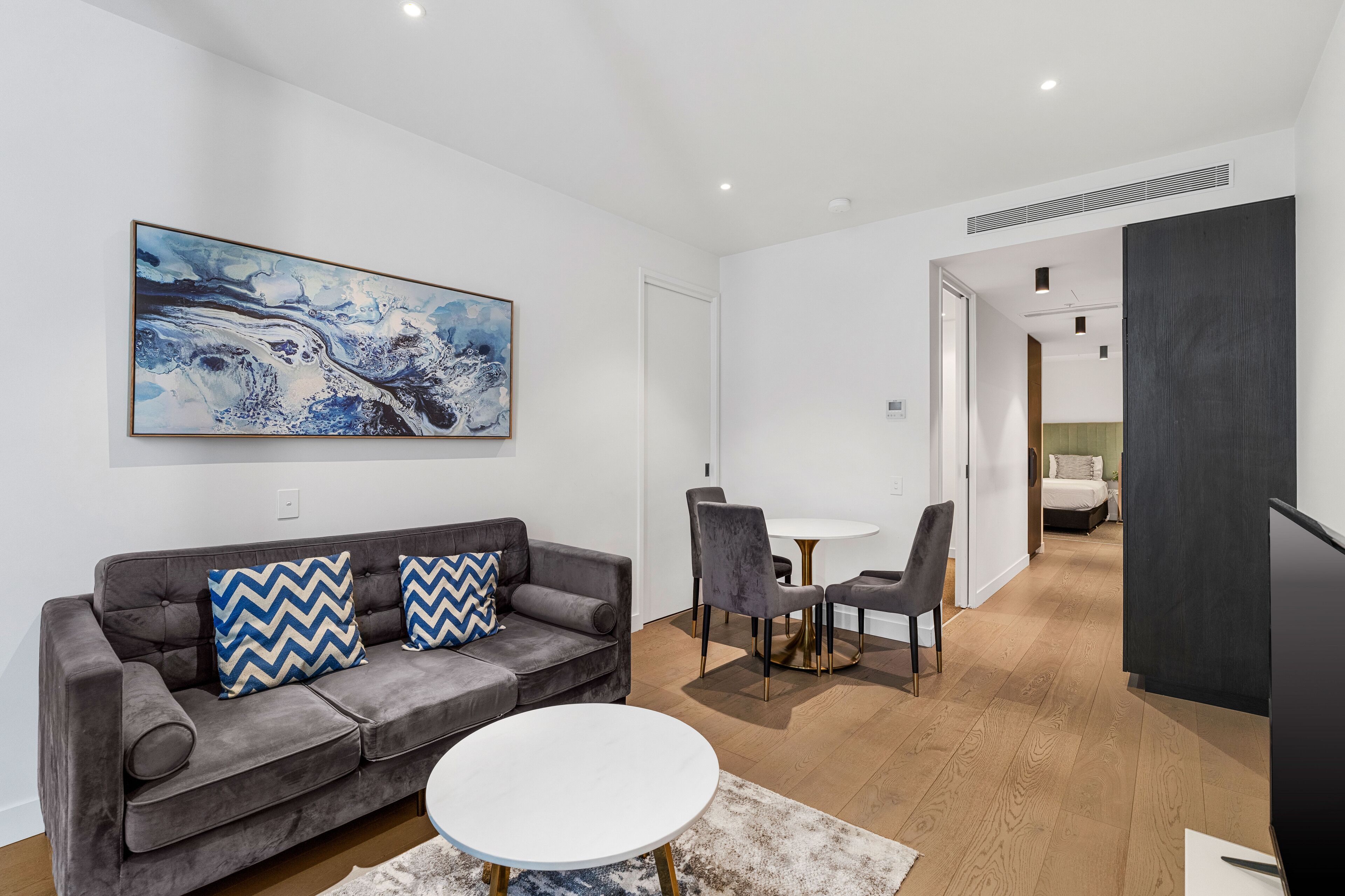 Ein modernes Wohnzimmer mit einem grauen Sofa, einem weißen Couchtisch und einem Gemälde an der Wand.