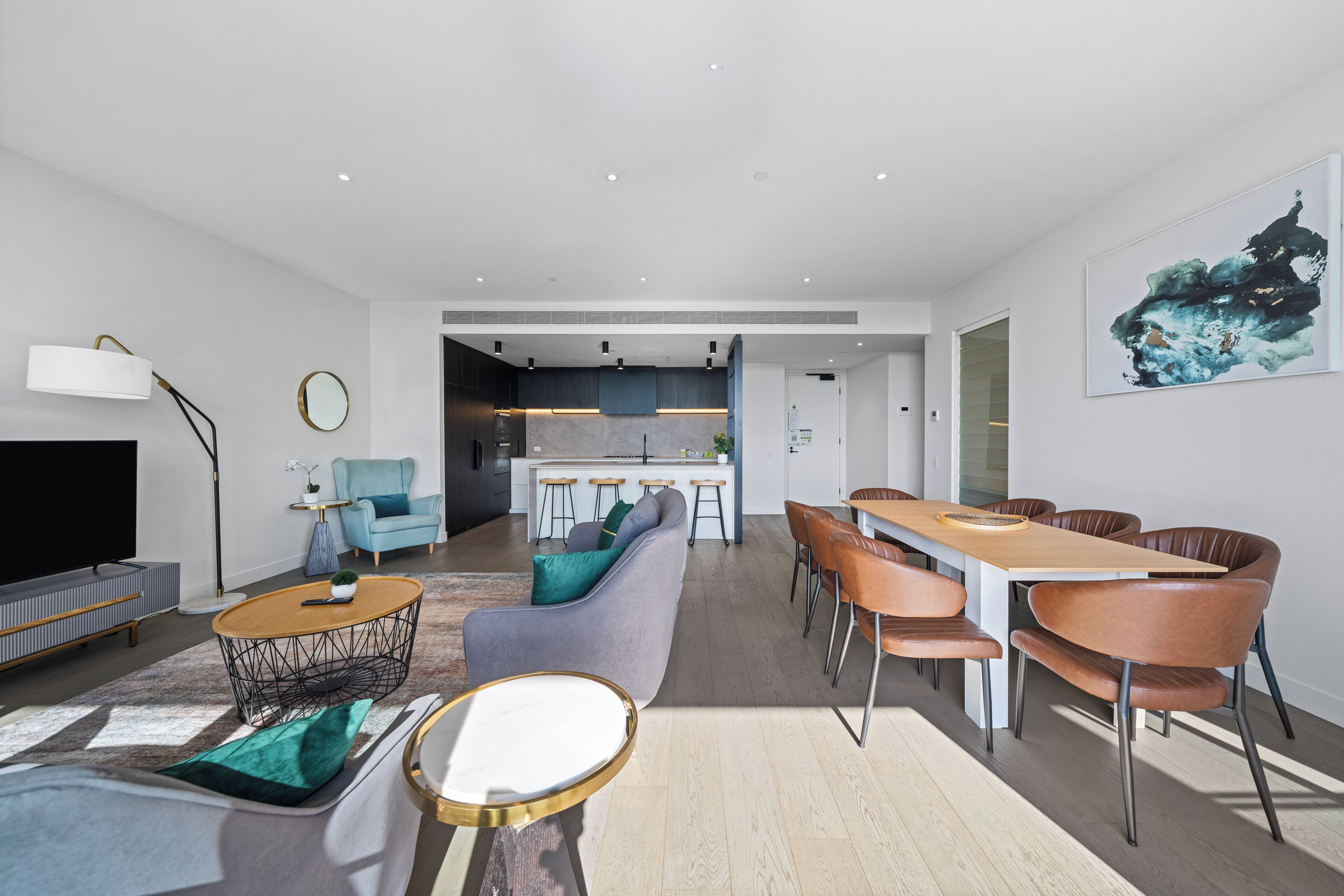 A modern living room with a sofa, coffee table, and dining area with chairs.