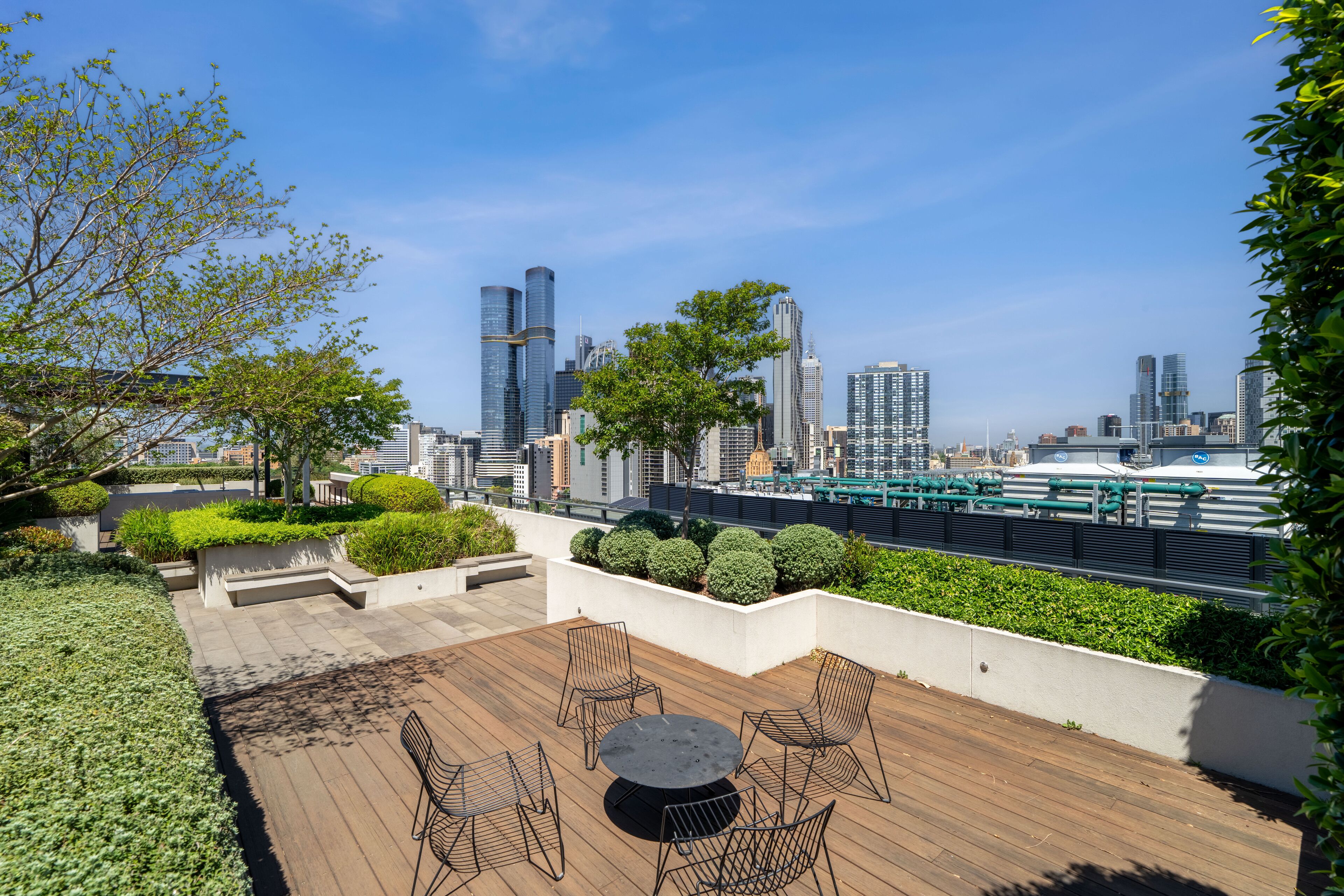 Eine Dachterrasse mit Holzboden, Sitzgelegenheiten und Blick auf eine Stadtlandschaft.