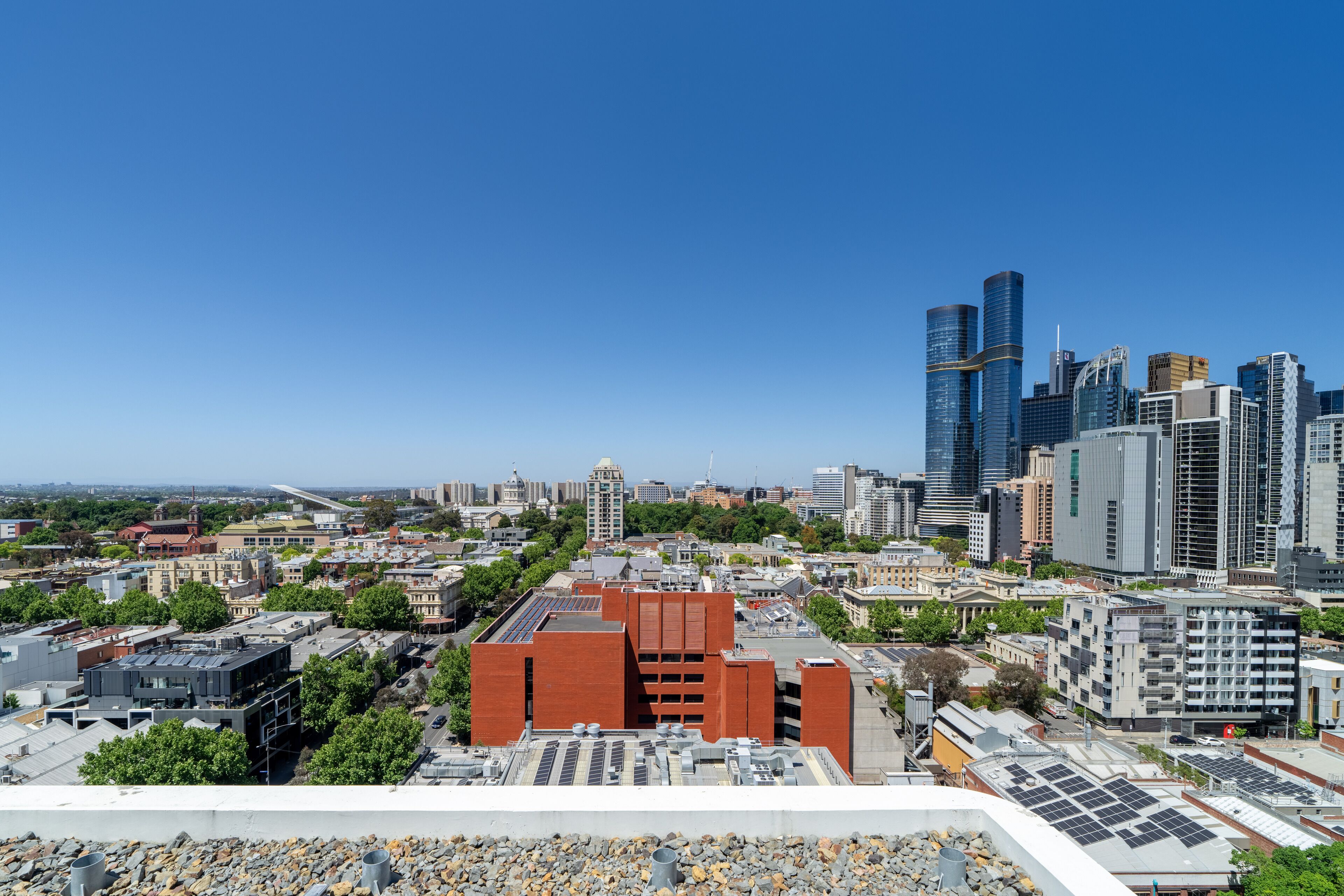 Un paysage urbain avec des bâtiments modernes, dont une imposante structure en briques rouges et de hauts gratte-ciel.