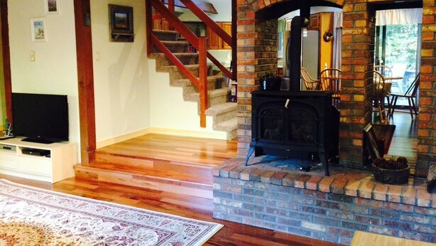 A living room with a fireplace, wooden staircase, and a flat-screen TV.