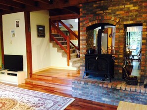 Una sala de estar con chimenea, una escalera de madera y un televisor de pantalla plana.