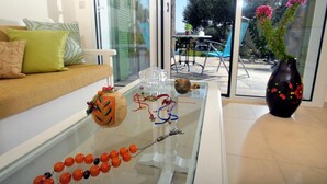 Una sala de estar moderna con una mesa de centro de vidrio, un sofá con cojines estampados y un jarrón decorativo.