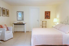 Une chambre à coucher avec un lit, un bureau, une chaise, une lampe et un tableau accroché au mur.