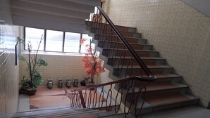 A staircase with a metal railing leading to an upper floor, surrounded by potted plants and decorative items. - Sakol Hotel Korat (Nakhon Ratchasima)
