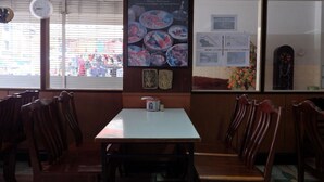 A restaurant interior with wooden booths, a poster of Thai cuisine, and a clock on the wall. - Sakol Hotel Korat (Nakhon Ratchasima)