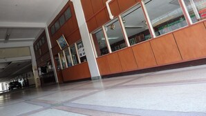 A spacious indoor area with a tiled floor, wooden paneling, and large windows. - Sakol Hotel Korat (Nakhon Ratchasima)