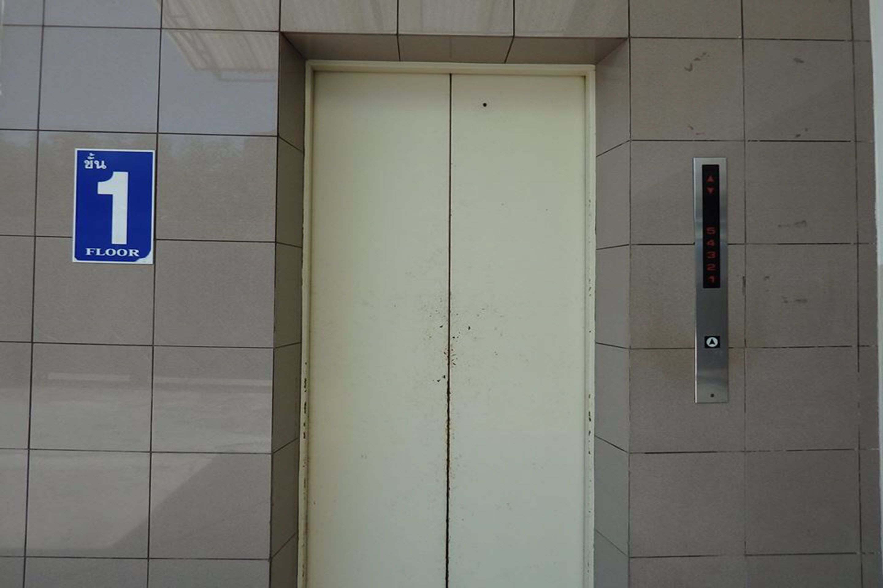 Porta de elevador com um aviso indicando o primeiro andar.