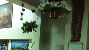 A room with a wooden bench, a potted plant, a decorative fountain, and wall-mounted artwork. - Sakol Hotel Korat (Nakhon Ratchasima)