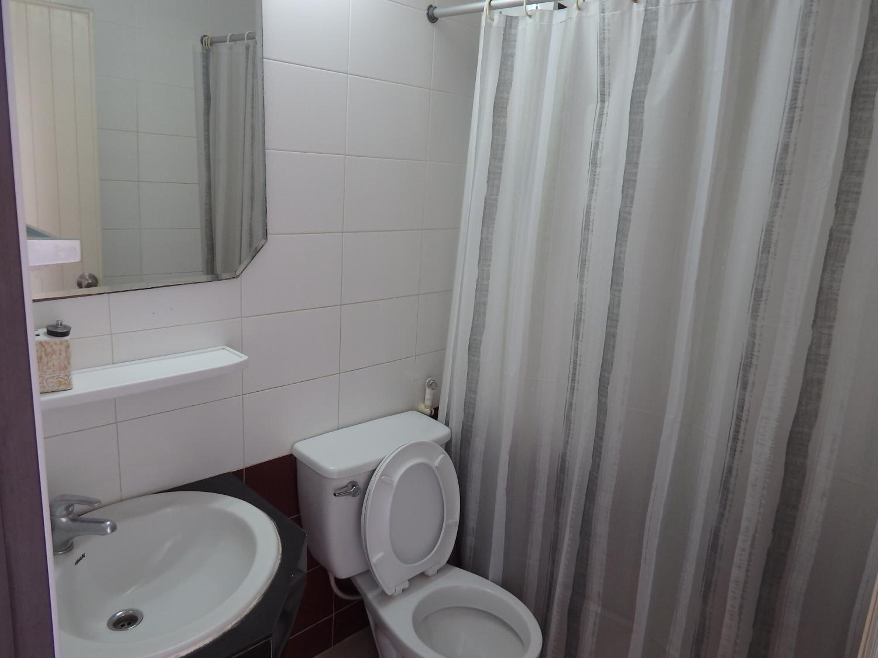 A bathroom with two toilets, a sink, a mirror, and a shower curtain.