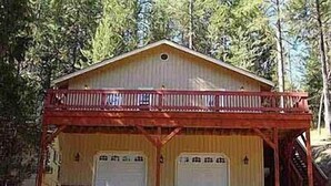 Un edificio de dos pisos con un balcón y dos puertas de garaje.