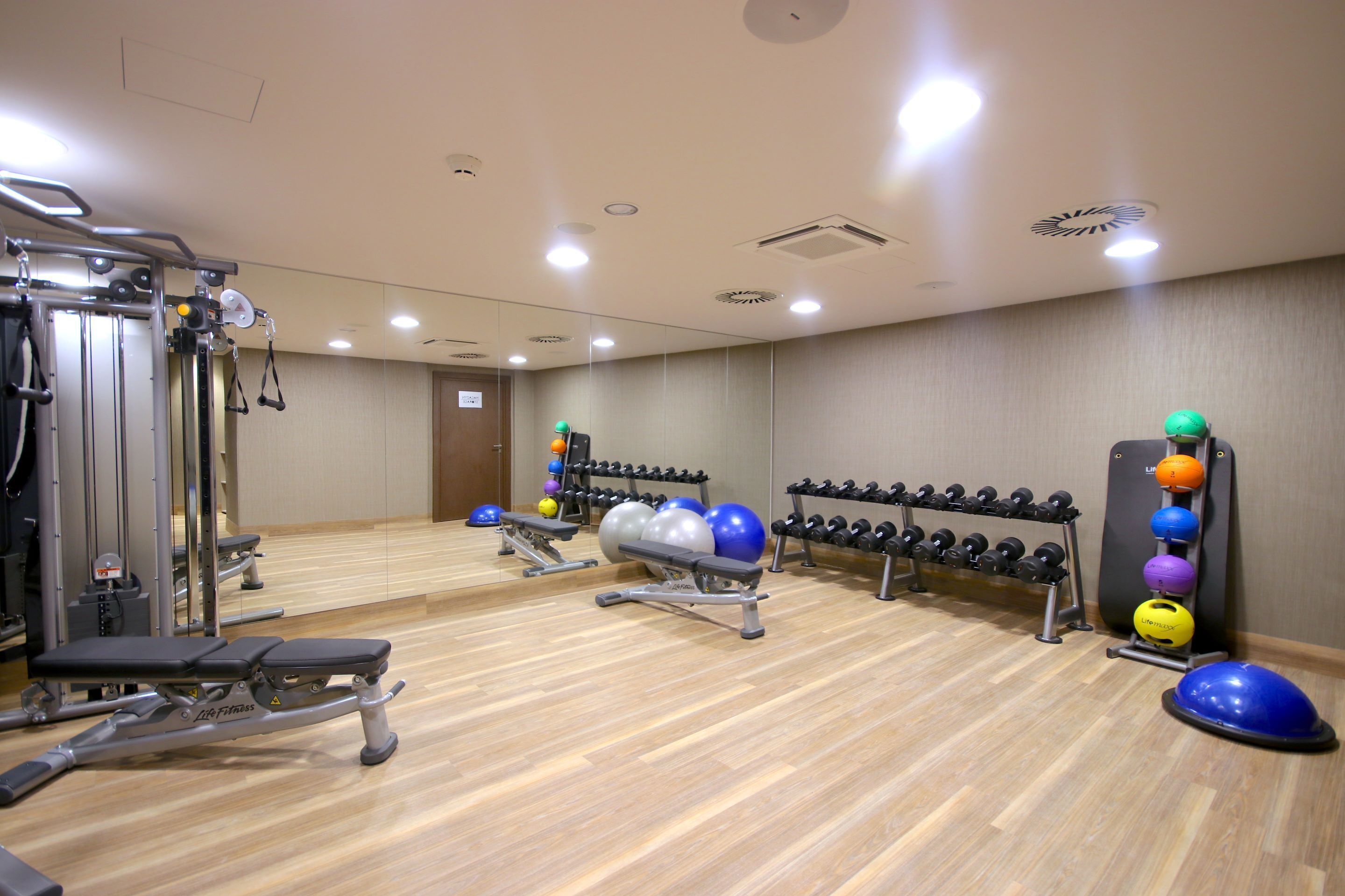 A gym with exercise equipment, a bench, and a wall-mounted dumbbell rack.